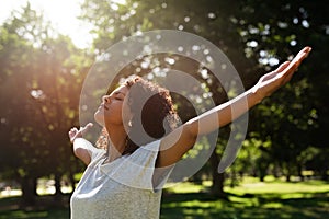 Woman standing in a park rasing her arms skyward