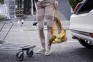 Woman standing at parking lot after plastic free shopping at supermarket.