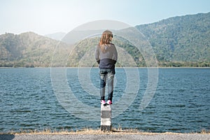 Woman standing on pillar roadside front of her have big lake and