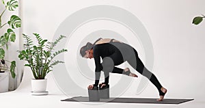 Woman standing in a plank and leaning her hands on small sports bricks, performs an exercise to strengthen the muscles