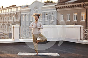 Woman standing in pose on mat and practicing yoga, female meditating outdoors