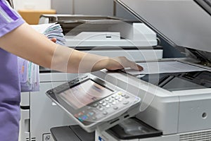 Woman standing and pressing button button on panel of printer, printer scanner laser office copy machine supplies in the office