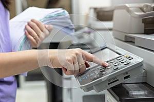 Woman standing and pressing button button on panel of printer, printer scanner laser office copy machine supplies in the office