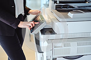 Woman pressing button on a copy machine in the office photo