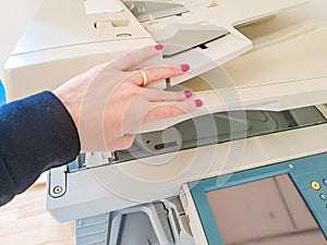 Woman standing and pressing button on a copy machine in the office