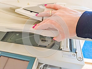 Woman standing and pressing button on a copy machine in the office