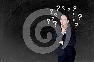 Woman is standing with question marks blackboard background