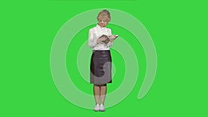 Woman standing and reading book on a Green Screen, Chroma Key