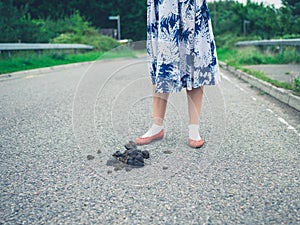 Woman standing in road by horse dung