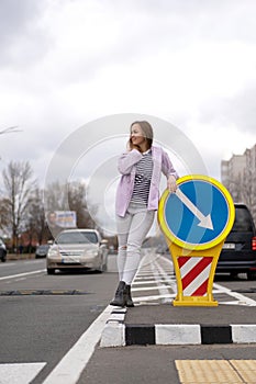 Woman standing on the road, laying on the road sign