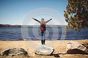 Woman standing on a rock, arms outstretched. Papineau Lake, Ontario, Canada photo