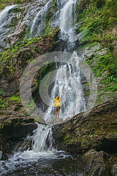 Woman standing on a rock with a waterfall in front