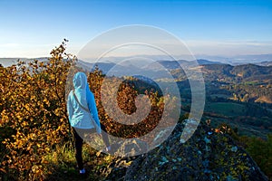 Woman standing on the rocks, enjoying the beauty of green hills. Kremnica Mountains, Slovakia.