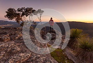 Woman standing on rocky mountain  ledge at sunset