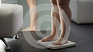 Woman standing on scales to see result of healthy dieting, normal weight range