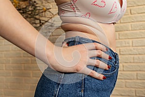 Woman standing sideways, folds on the abdomen