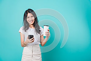Woman standing smile, using mobile phone her holding coffee paper cup