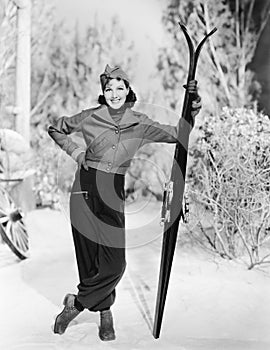 Woman standing in the snow with her skies in hand