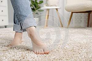 Woman standing on soft carpet at home, closeup. Space for text
