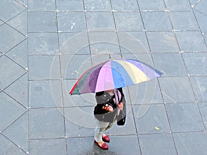 Woman carrying colorful umbrella - rainbow colors - monsoon scene - rainy season