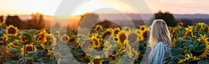 Woman standing in sunflower field during sunset