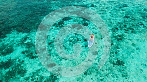 Woman standing on sup board. Turquoise water drone