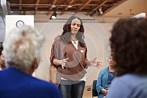 Woman Standing To Address Self Help Therapy Group Meeting In Community Center