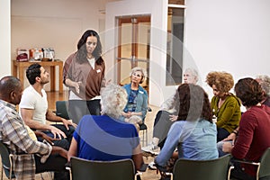 Woman Standing To Address Self Help Therapy Group Meeting In Community Center