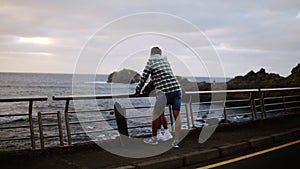 Woman and standing together, looking on ocean - Young couple shown from the side look out over an ocean in front of the