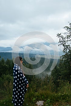 Woman standing on top of a hill, against the background of a valley