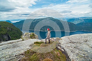 A woman standing on the top of the hill over the view of fjord