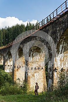 Woman standing under ancient railway viaduct in Vorokhta village, Ukraine