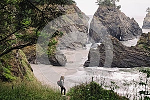 Woman standing with a view to a secret beach in Oregon coast. Hiking at the Pacific Northwest