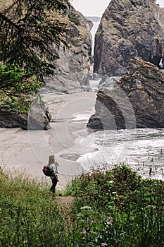 Woman standing with a view to a secret beach in Oregon coast. Hiking at the Pacific Northwest