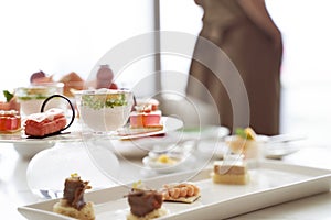 Woman standing by window with assorted desserts on table