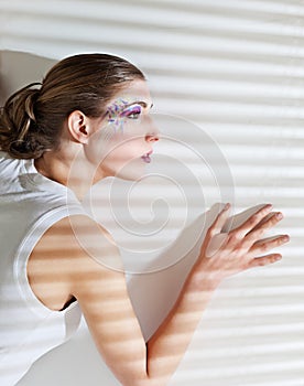 Woman standing by the window with blinds