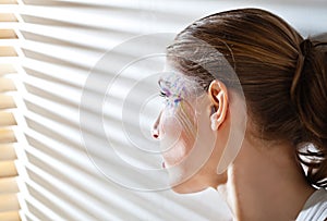 Woman standing by the window with blinds