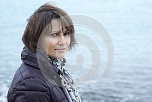 Woman standing in windy conditions in front of the sea