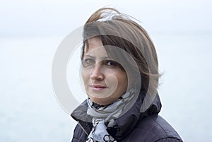 Woman standing in windy conditions in front of the sea