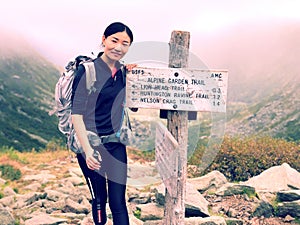 A woman standing by a wooden marker on Mt. Washington