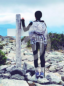 A woman standing by a wooden marker on Mt. Washington