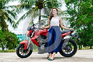 Woman standng near her motorcycle on palm background