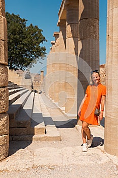 A woman stands in the ancient acropolis of Lindos against the background of the colonade, Greece, Rhodes