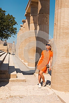 A woman stands in the ancient acropolis of Lindos against the background of the colonade, Greece, Rhodes