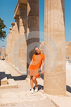 A woman stands in the ancient acropolis of Lindos against the background of the colonade, Greece, Rhodes