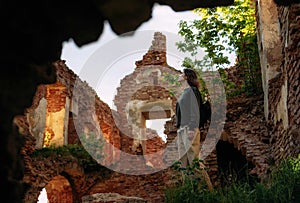 Woman stands by archway of old castle building, Halshany, Belarus
