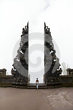 A woman stands at the Balinese traditional gate in the clouds at the sacred temple of Pura Pasar Agung Sebudi on Mount Agung photo