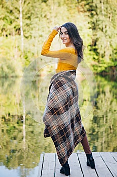 Woman stands on a bridge on a lake with an autumn landscape