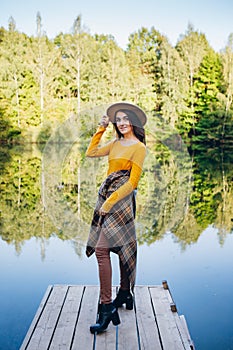 Woman stands on a bridge on a lake with an autumn landscape