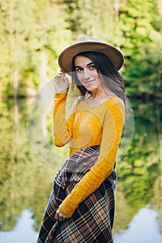 Woman stands on a bridge on a lake with an autumn landscape